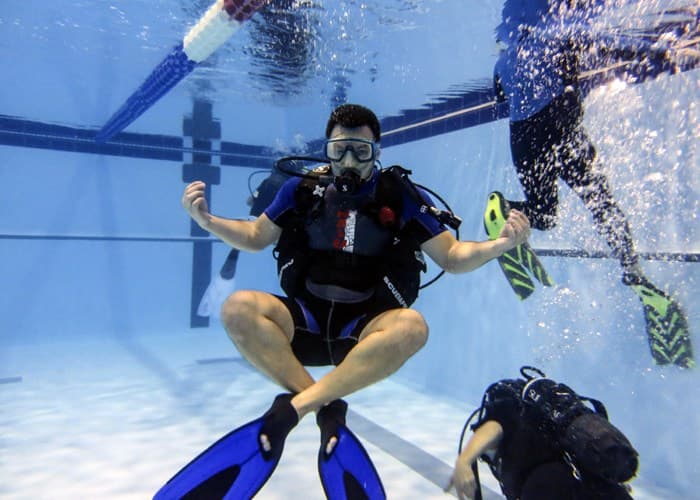 Cursant plutind neutru în piscină, cu mâinile deschise