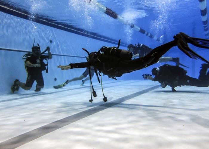 Scafandru înotând orizontal deasupra fundului piscinei