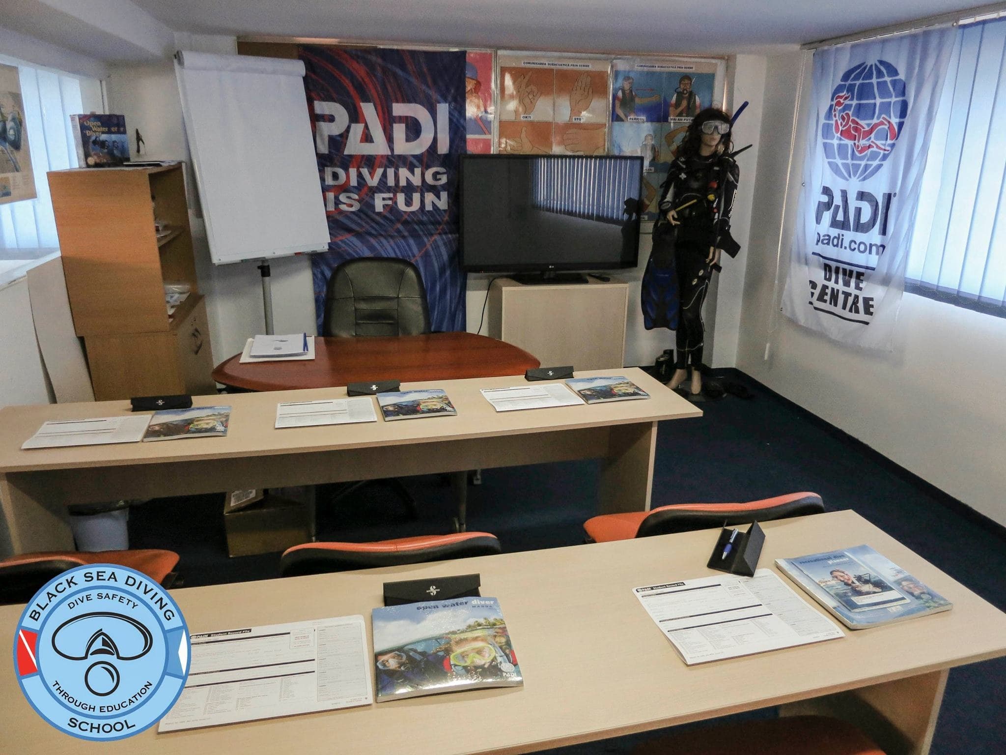 Sala de curs din București, cu mese, ecran și materiale PADI